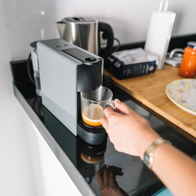 woman-holding-glass-mug-coffee-machine